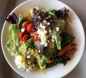 A vibrant, farm fresh salad in a crisp white bowl, bursting with color and flavor. This healthy dish features a bed of mixed greens, topped with juicy cherry tomatoes.